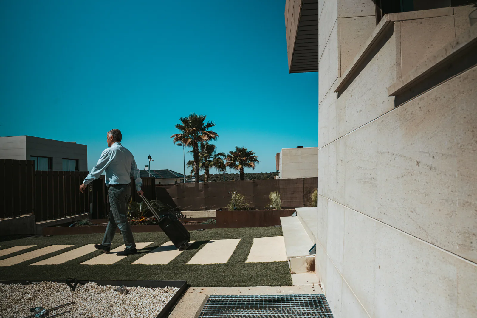 Persona caminando junto a una vivienda contemporánea y un jardín mediterráneo